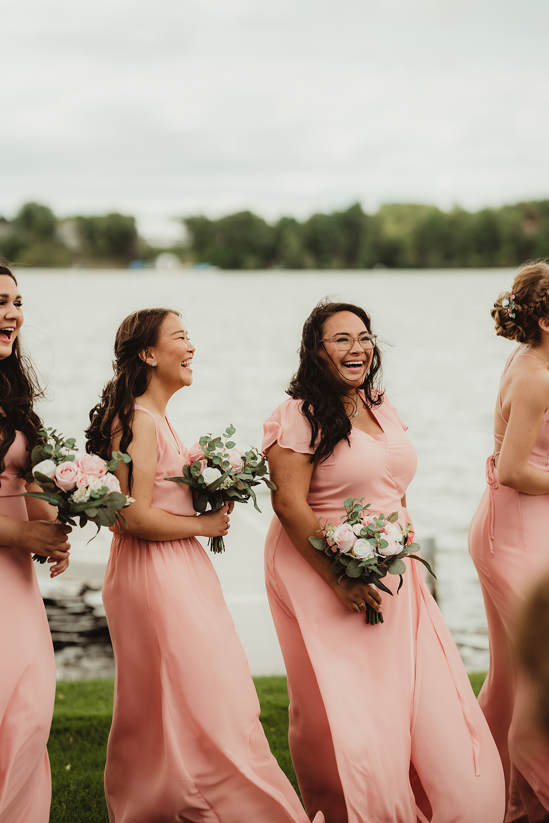 The bridesmaids laugh together in their blush pink bridesmaids dresses during a Wisconsin wedding ceremony. Lake wedding Pink bridesmaids Bridesmaids florals #wisconsinweddingphotographer #choosingaphotographer #lakesidewedding #waterfrontweddingceremony