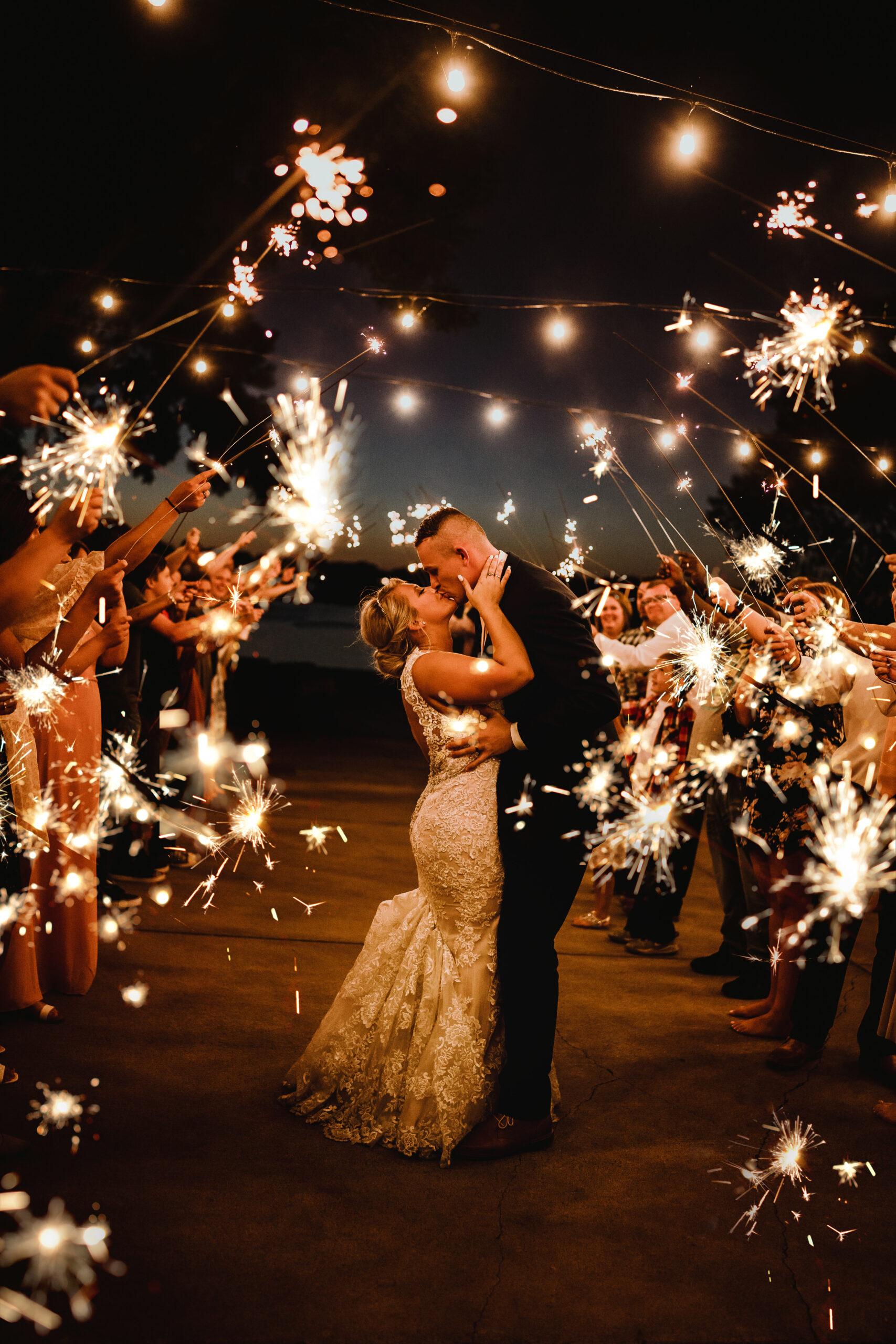 Bride and groom kiss during their wedding reception exit with sparklers held by their wedding guests. Sparkler exit photos Wedding reception photography Bride and groom pose #wisconsinweddingphotographer #choosingaphotographer #lakesidewedding #waterfrontweddingceremony