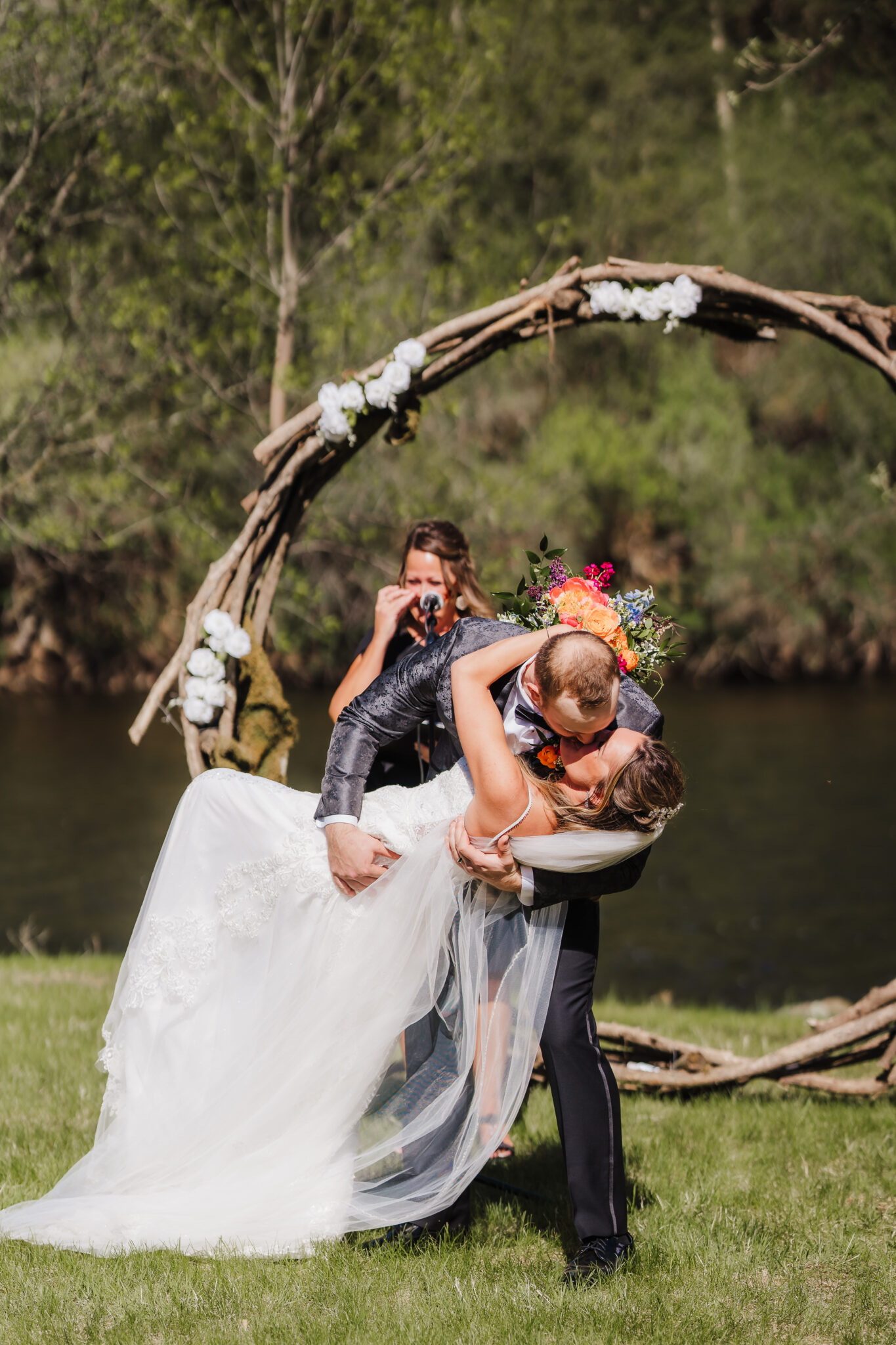 A Wisconsin bride and groom share a kiss in front of a rustic circle arch as the officiant says you may now kiss the bride. Wedding ceremony photos Wedding arch #forestgreenwedding #rusticweddingvenue #weddingplanning #wisconsinweddingphotographer #wisconsinweddingvenue