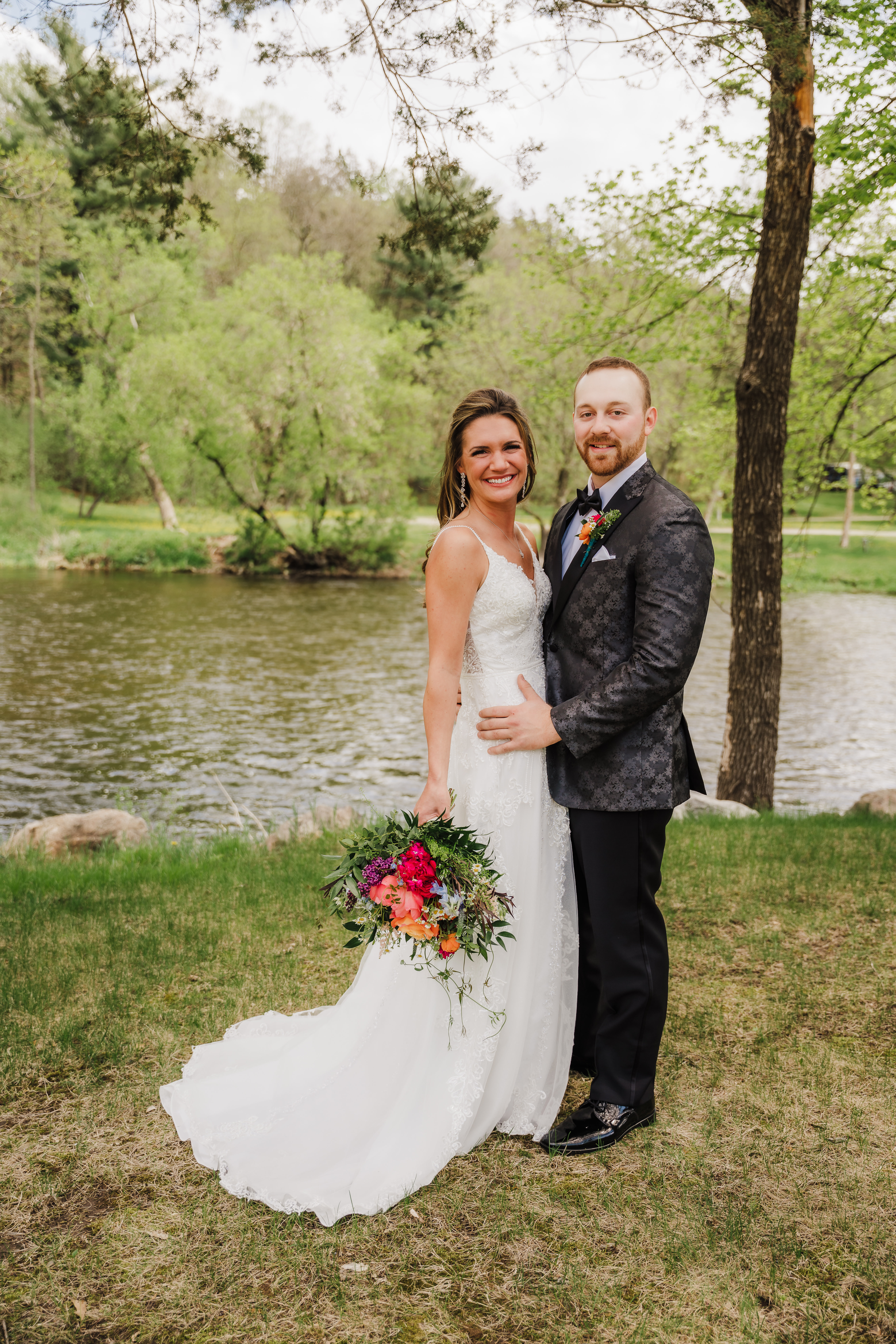Newlywed bride and groom pose by the water with her bright pink wedding bouquet. Wisconsin summer wedding Pink wedding scheme Bridal poses #forestgreenwedding #rusticweddingvenue #weddingplanning #wisconsinweddingphotographer #wisconsinweddingvenue