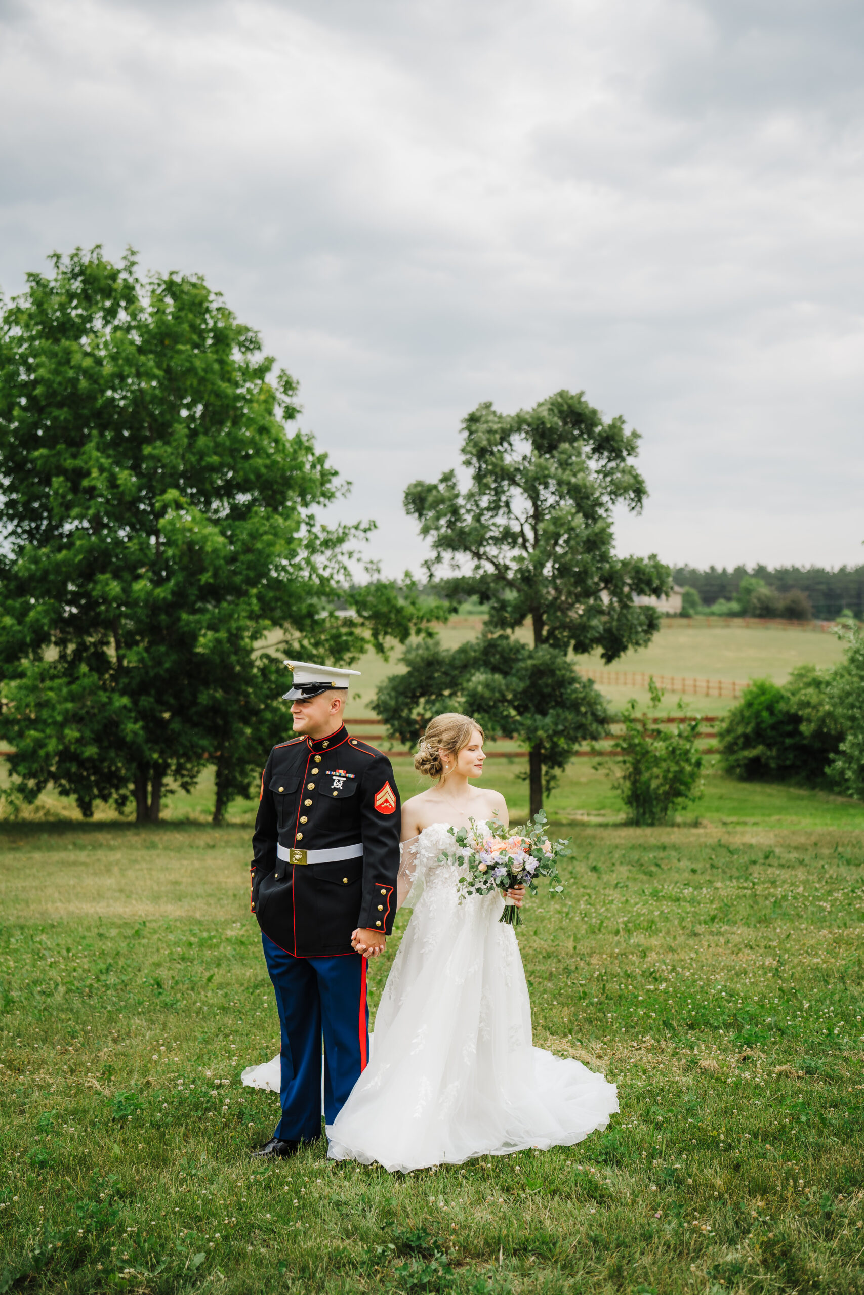 A military groom and his new bride pose in a green field with her burnt orange florals. Couple poses Military wedding Bride and groom photos Bridal portraits #weddinginspiration #weddingplanning #diywedding #wisconsinweddingphotographer #armywedding