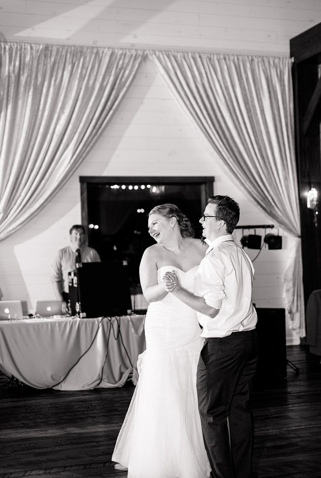 A bride laughs as her and her husband dance to their first dance song. 