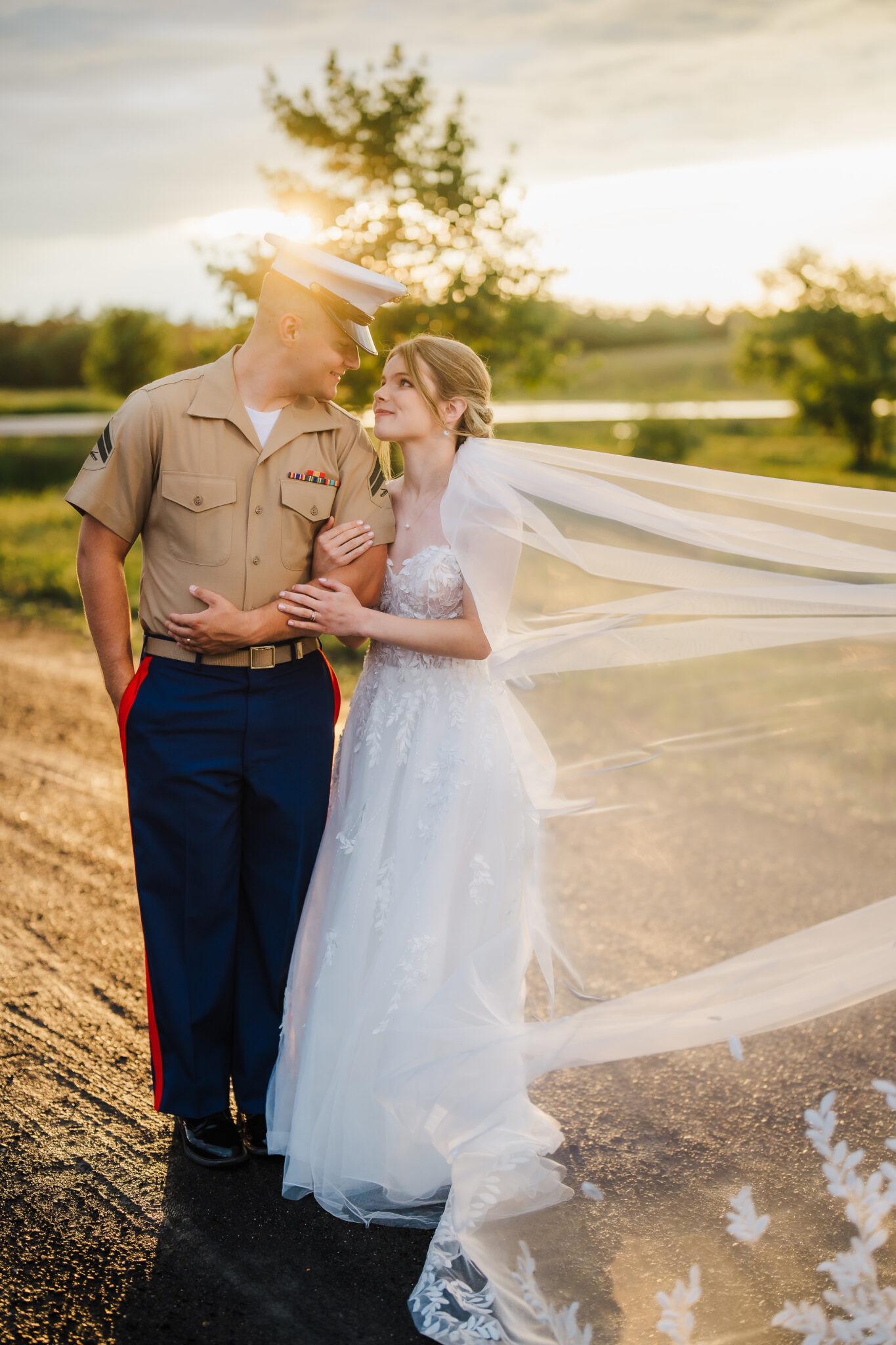A military wedding couple stare into each others eyes as the sun sets behind them. 