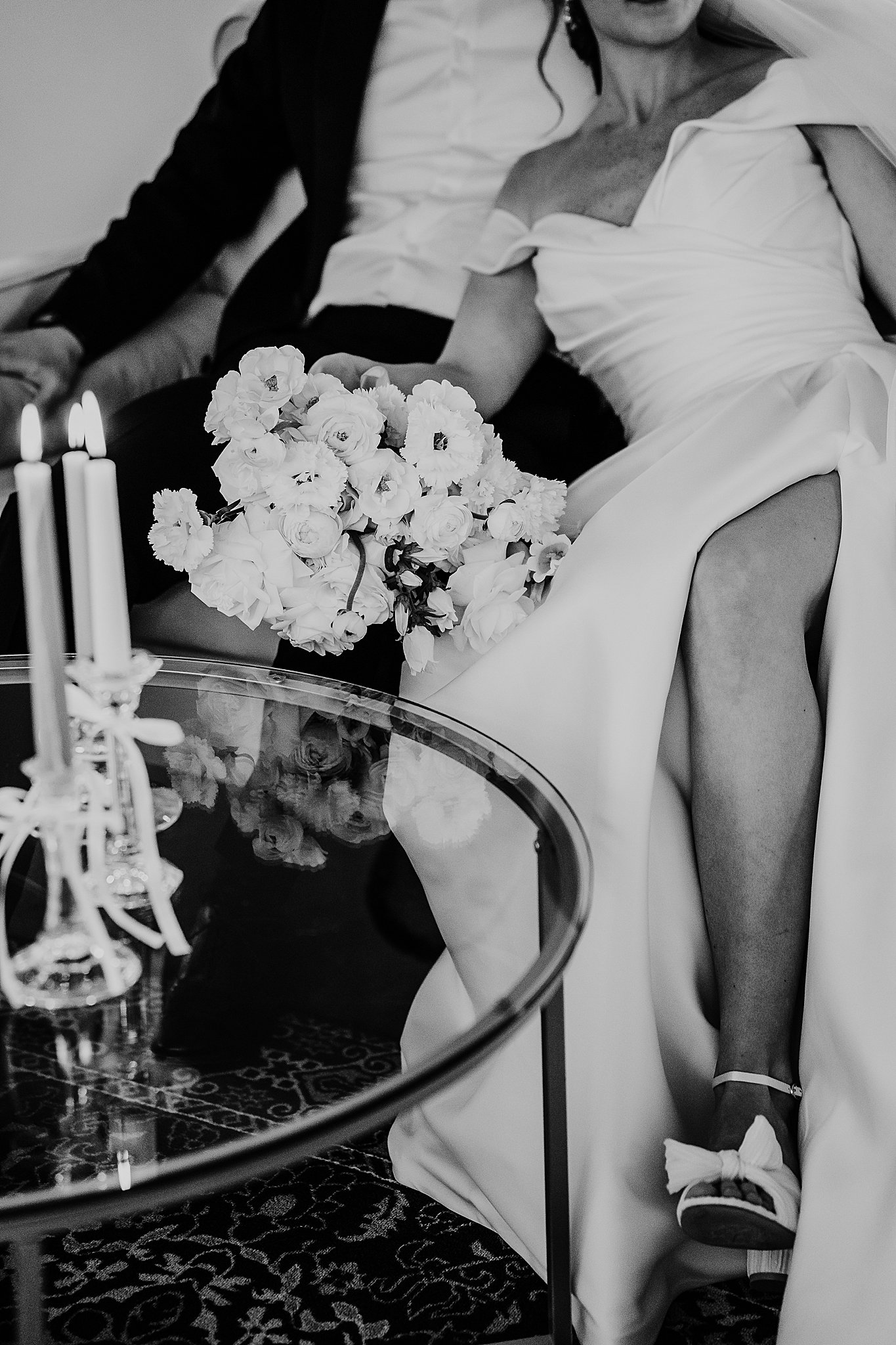 A detail shot of the slit of brides dress as she snuggles with her husband and the bouquet rests on her lap.