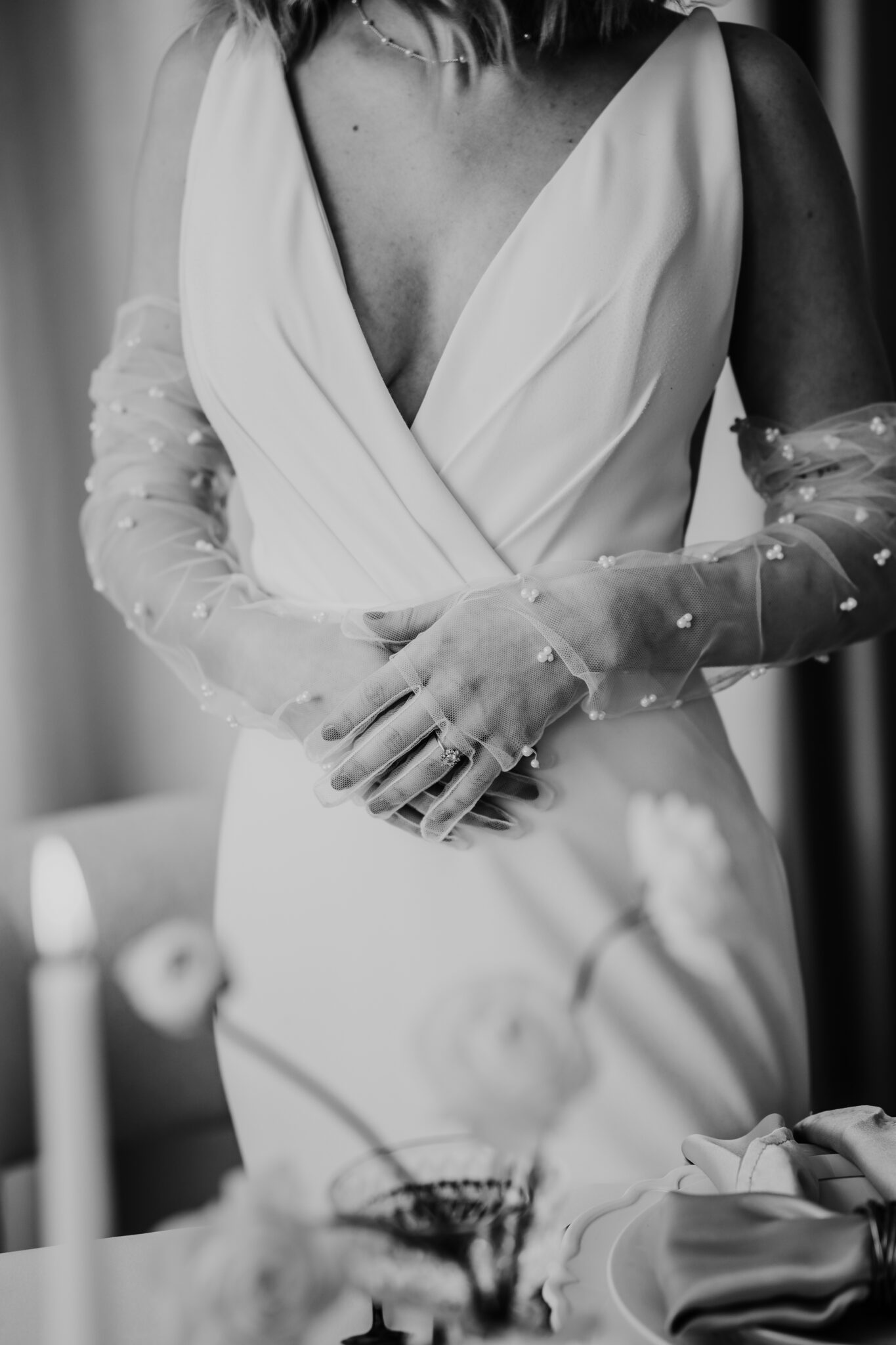 A shot of a beautiful bride wearing trendy gloves and a deep v simple wedding dress. 