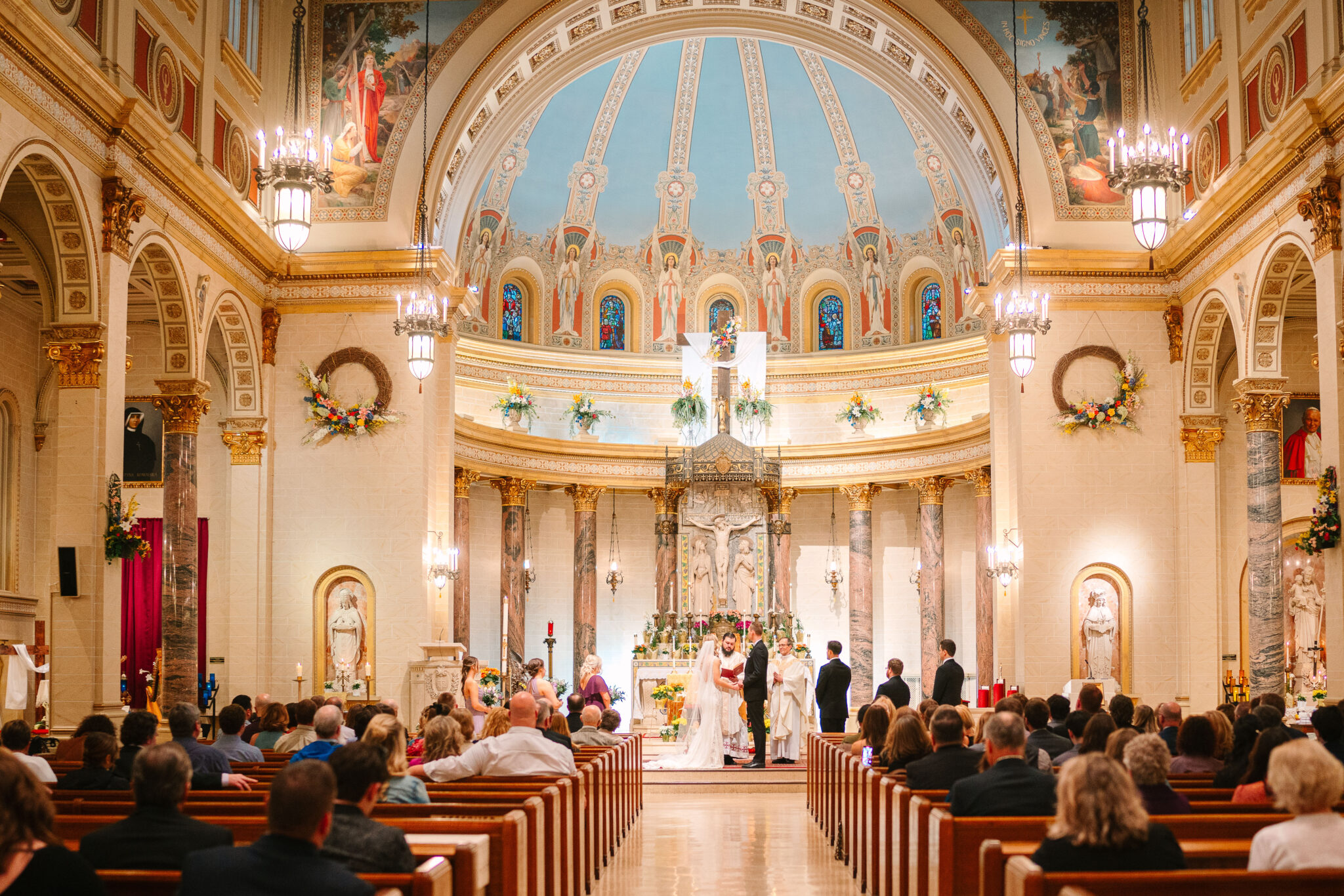 A vibrant wedding ceremony inside St. Paul Cathedral, showcasing the ornate altar, detailed frescoes, and grand dome, with a bride and groom exchanging vows surrounded by loved ones, celebrating faith, love, and commitment in a timeless sacred space