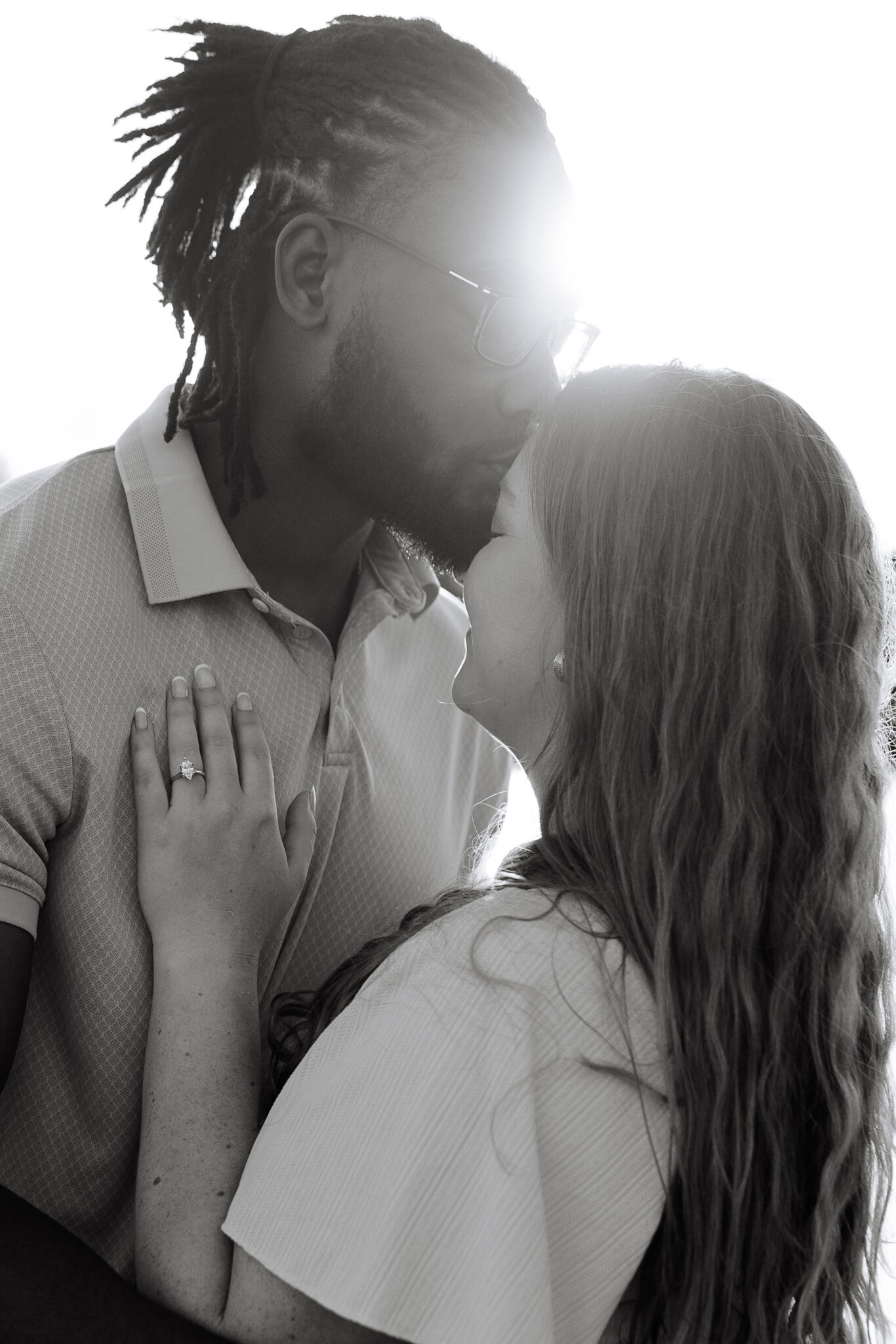 A couple shares a kiss in Eau Claire Wisconsin as the sun bounces off of them at Phoenix Park