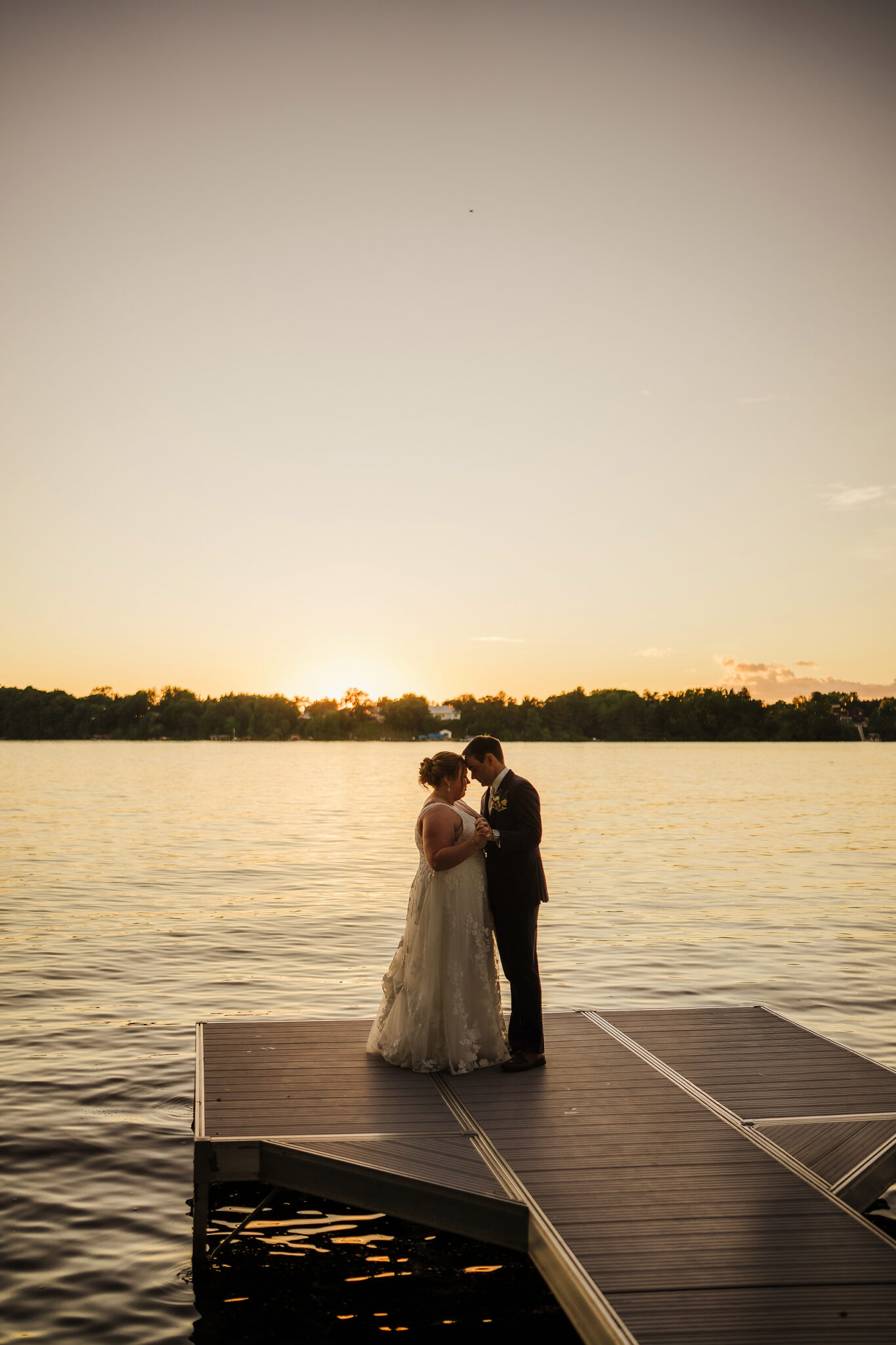 A couple snuggle as the sun sets on their wedding day at Lake Wissota Golf.
